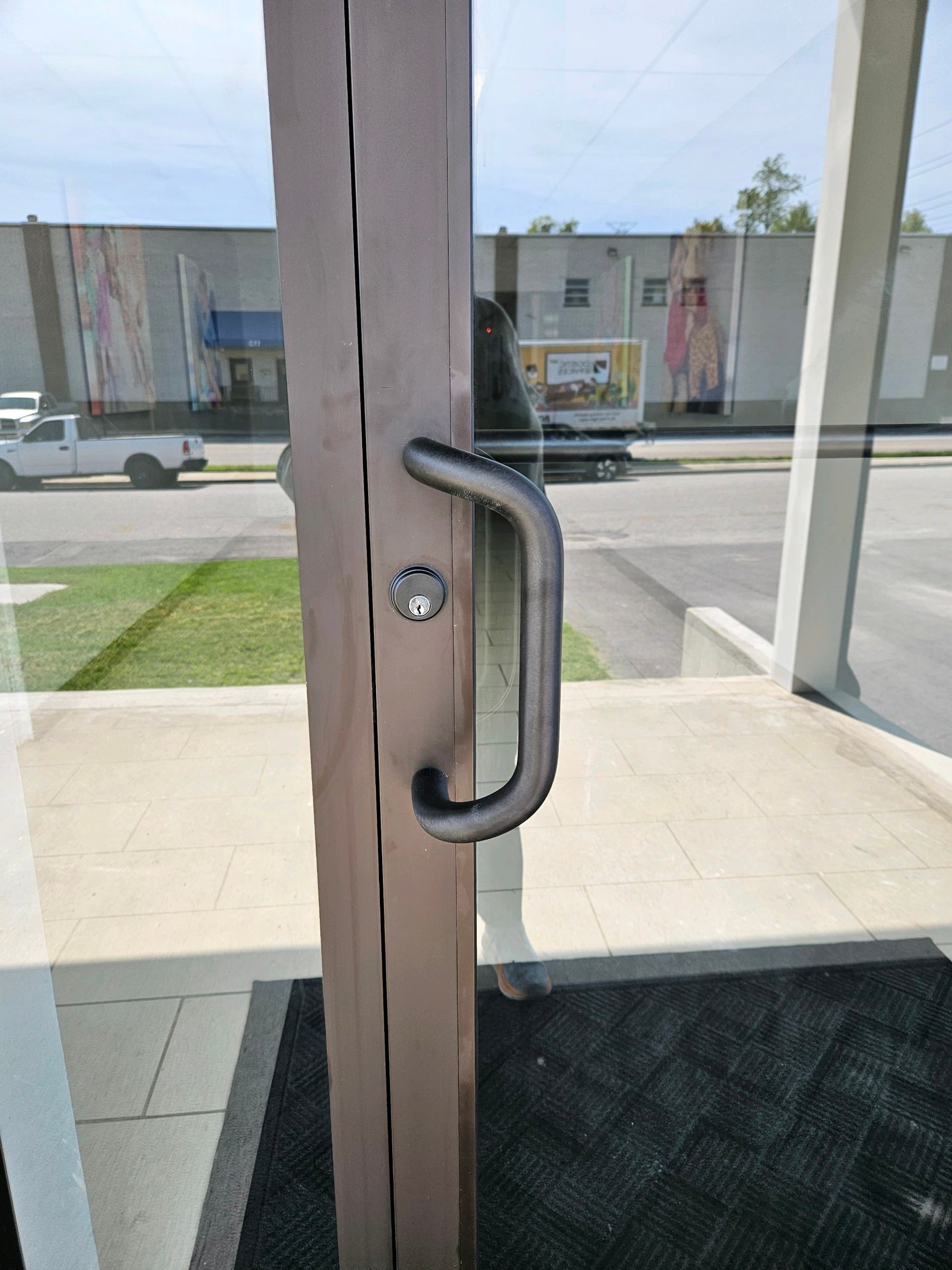 Commercial glass storefront door with matte black pull handle and silver deadbolt cylinder, professionally installed by Recommended Locksmith in Maryland